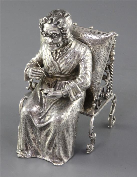 A late 19th century German Hanau silver model of an elderly lady sewing, seated in an ornate antique chair, 15 oz.